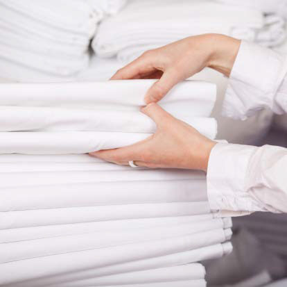 Closeup of white bedsheets stacked in store room of hotel