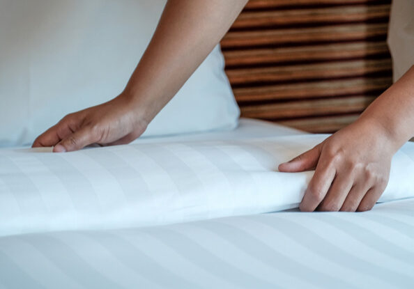 Hands of hotel maid making the bed in the luxury hotel room ready for tourist travel.